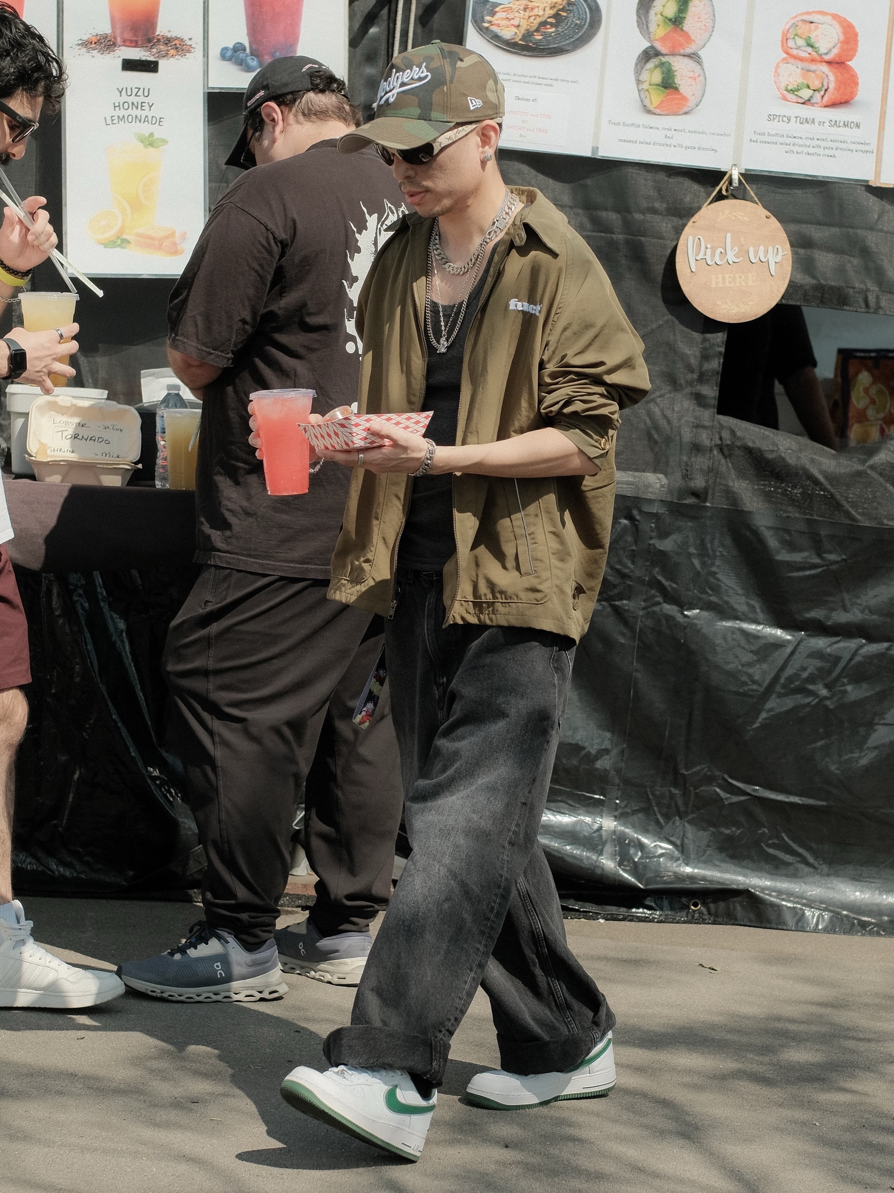 Olive utility jacket over a black tank, layered silver chains, camo cap, at Spinning Sunset
