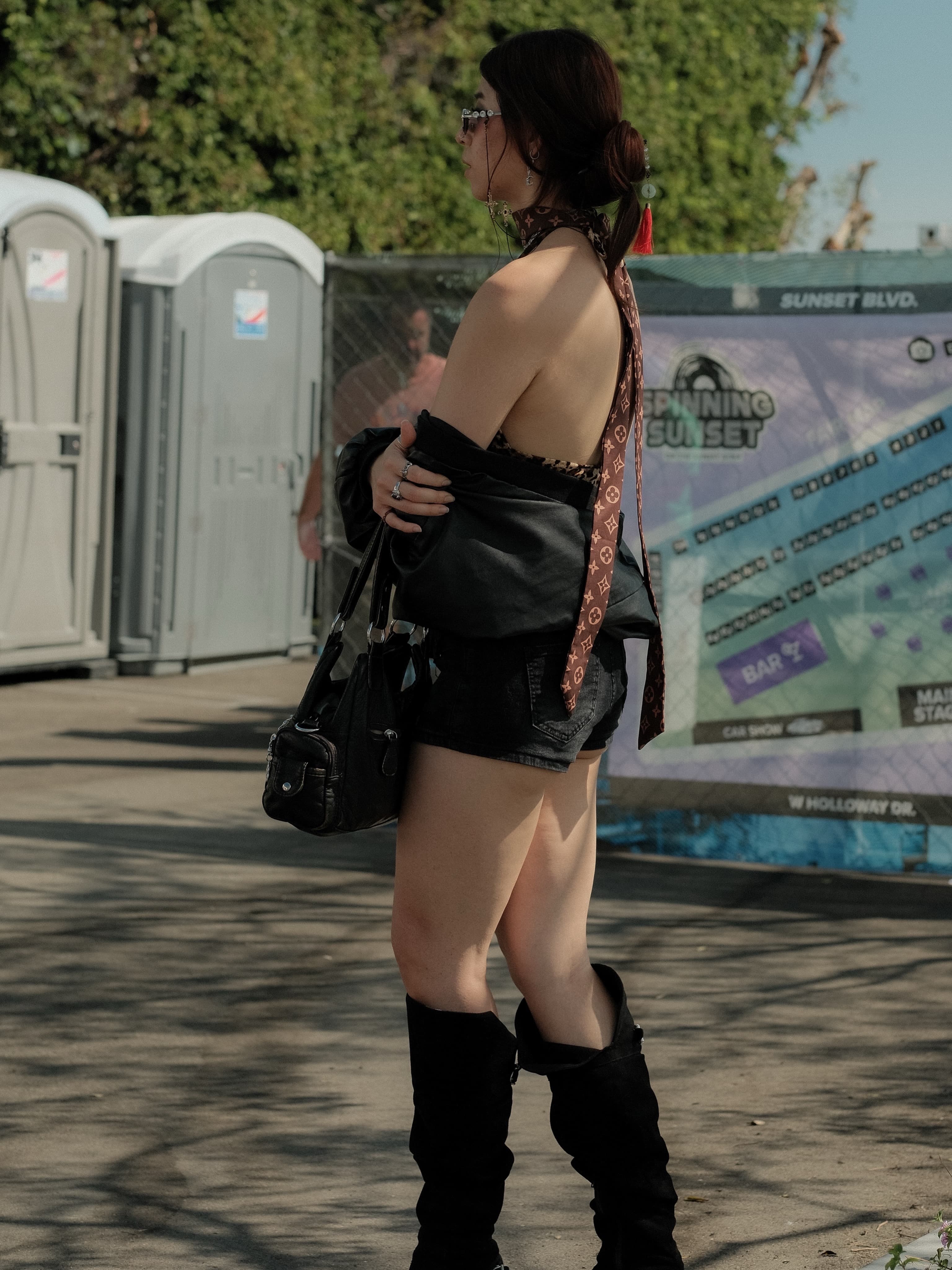 Black off-shoulder top, denim shorts, a printed silk scarf tied at the neck, at Spinning Sunset