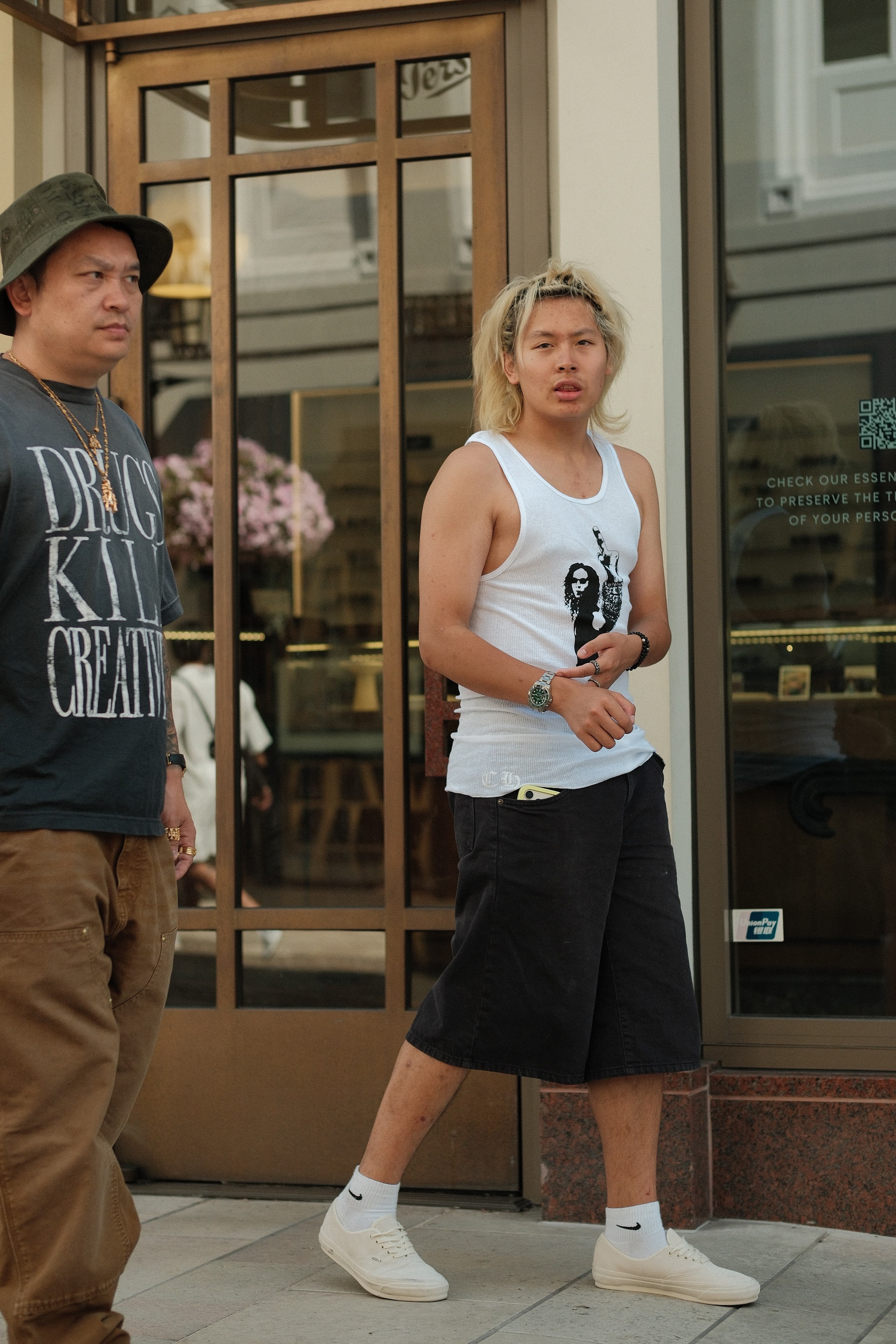 Graphic tee, tan cargo trousers, gold chains, bucket hat, next to a photo-print tank and denim shorts